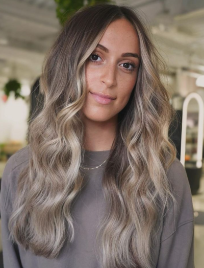 Woman with soft blonde highlights styled at Salon Beau, emphasizing natural, low-maintenance beauty.