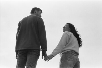 couple hold hands with the sky as a background