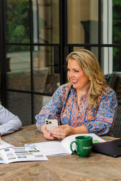 women wearing a pink and blue dress with patterns looking at someone off camera and holding a phone during branding with Laure Photography Atlanta