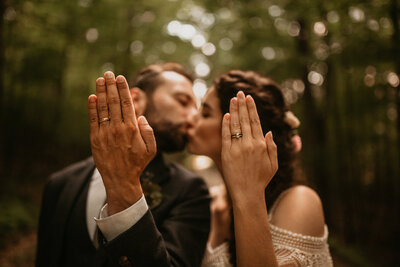 bride and groom kissing and showing off their rings