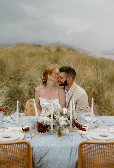 Elopement at Cape Kiwanda with couple laughing and cuddling in the sand dunes.