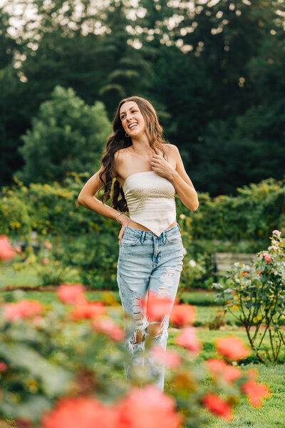 High school girl in white dress, smiling off camera in field of flowers