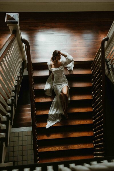2 brides sit in a vintage getaway car one wearing a tux and one wearing a white gown. There are disco balls outside the car of varying sizes . Photo taken by Amelia Island wedding photographer