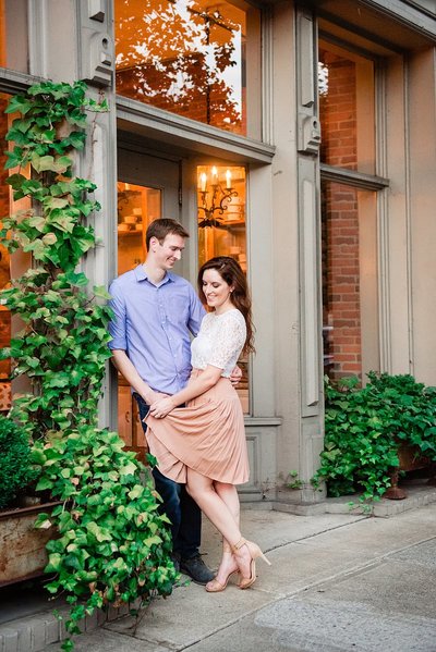 Bride in blush skirt and white top snuggled with her fiance by ivy outside a building in downtown Franklin Tennessee