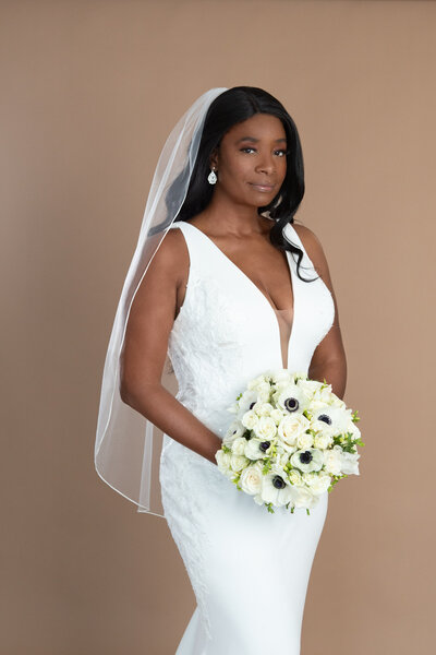 Bride wearing a short ribbon edged veil and holding a bouquet