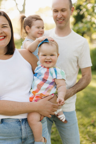 Brunette mother and father swinging daughter at park