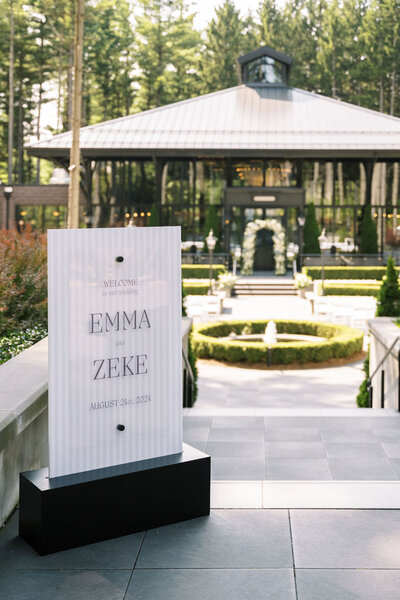 A bright and airy neutral wedding venue photo of the main dining area with brown chairs and white flowers during an alyssa amez design custom wedding