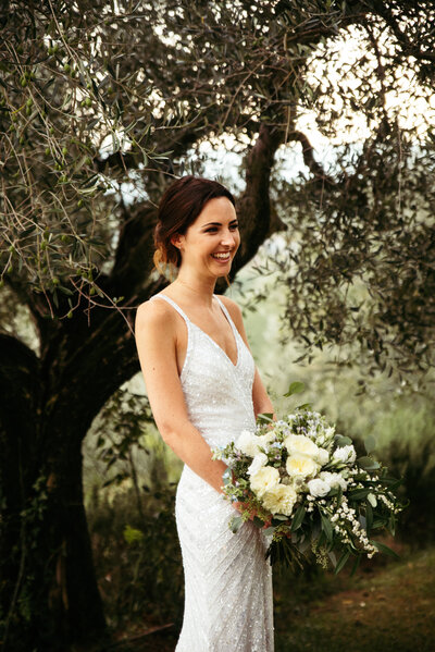 The bride smiles, surrounded by the breathtaking beauty of Tuscan nature, capturing a moment of pure happiness against the scenic backdrop of rolling hills and lush landscapes