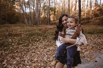 A parent holding their child as they smile and walk along a trail 