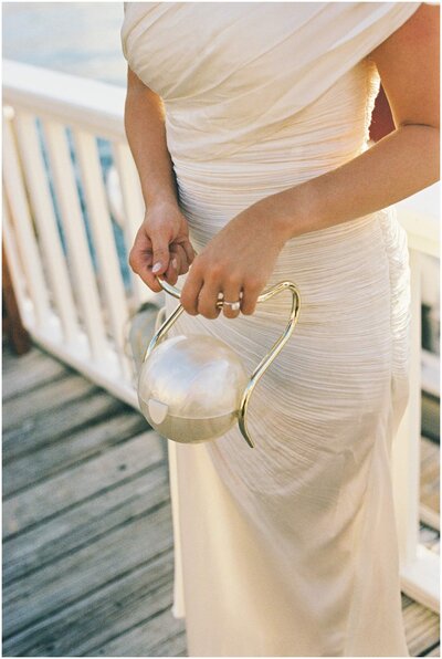 Details of a bride holding a pearl and gold handled ring box
