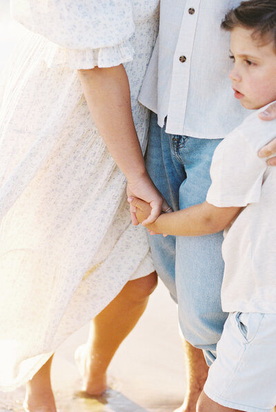 A sweet moment of a family holding hands during a beach session in Dallas.