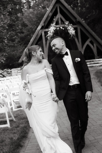 a couple sitting at the beach together. She is resting her head on his shoulder and their feet are in the sand. 