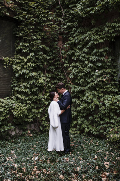 A bride and a groom kissing in a forest
