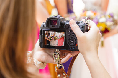 female photographer holding camera and taking photos of a wedding