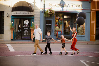 A family walks hand in hand through the charming streets of downtown Sewickley, smiling and enjoying their time together. The brick sidewalks, boutique storefronts, and tree-lined streets create a warm and inviting atmosphere, capturing a candid moment of love and connection.
