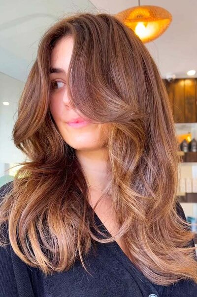 Brunette balayage styled in voluminous blowout layers with warm highlights, captured at Blake & Kwan Caringbah.