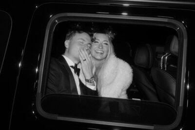 Bride and groom in getaway car blowing kisses