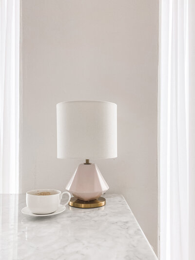 White cup and flower vase on top of white marble table