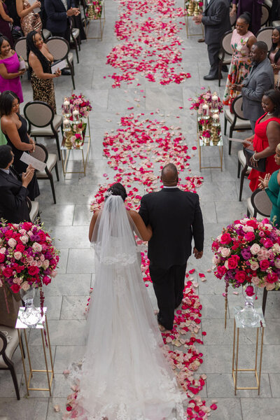 bride and father of the bride walking down aisle with pink rose petals