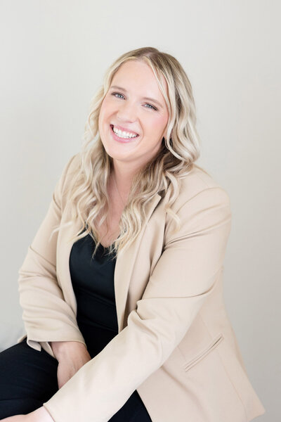 Becca smiling wearing an off white blazer.