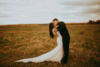Moody portrait of couple kissing in a field, captured by Jordan Conarroe Photography, vibrant and romantic wedding photographer in Edson, Alberta. Featured on the Bronte Bride Vendor Guide.