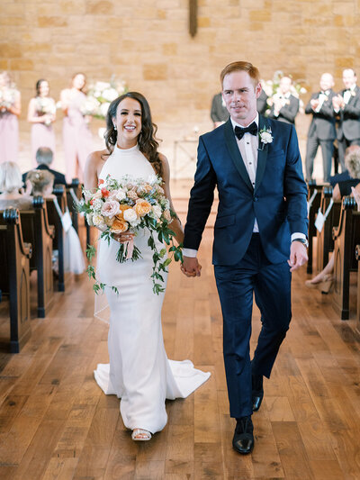 Bride and groom walk down the aisle smiling after their ceremony, celebrating a joyful Austin wedding planned with ease and expertise.
