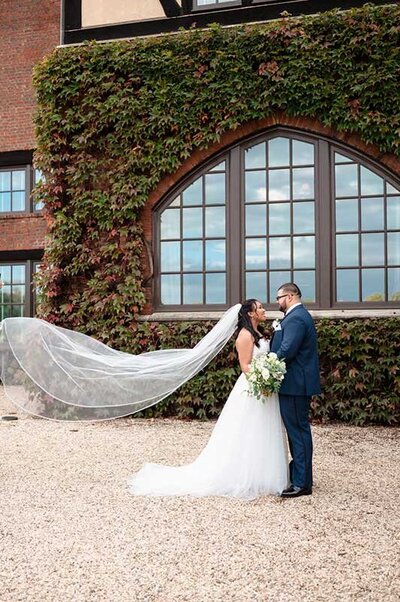 Bride and groom in from of ivy covered brick mansion