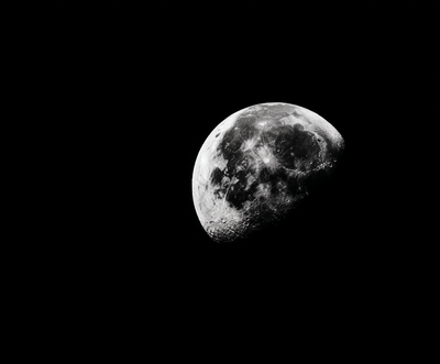 Cinematic black-and-white photo of a half moon glowing against a deep black sky, symbolizing mystery, intuition, and the start of a transformation journey in Jasmina Kimova’s podcast Episode 001