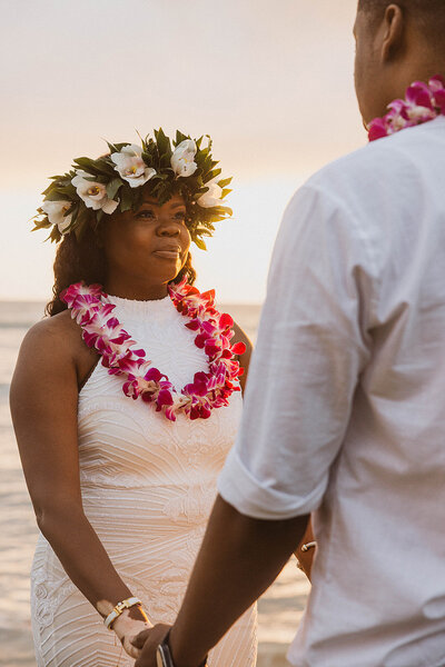 couple holding hands looking at eachother bride wearing flower crown and lua