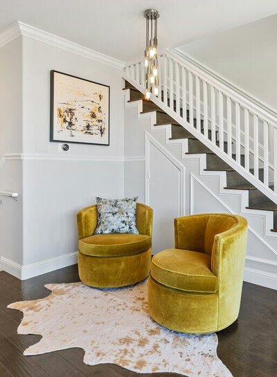 A foyer of an Atlanta, Georgia house, that shows yellow chairs, a stairway, and a rug