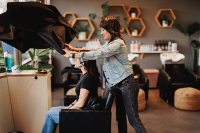 Chelsea throws a cape over a client at her salon in Eugene Oregon.
