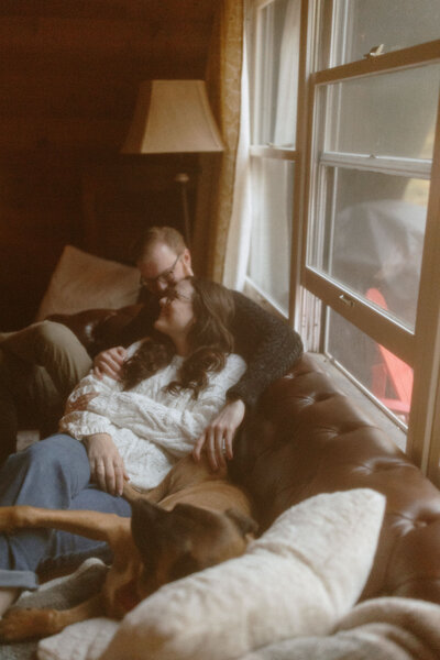 couple cuddle on couch with dog in Poconos cabin