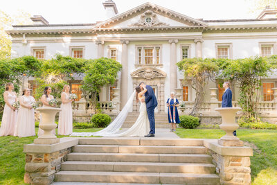 A couple shares their first kiss and Liriodendron Mansion Wedding Photographer captures the moment on the mansion steps