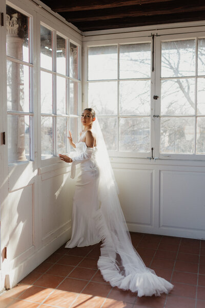 photo of bride standing in front of large windows taken by