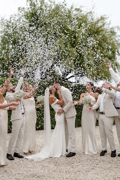 bride and groom kissing with confetti thrown over them