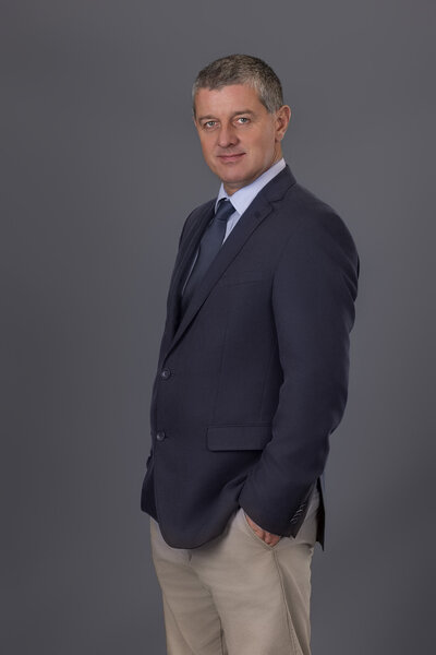 corporate headshot of business man with navy suit jacket on a dark background