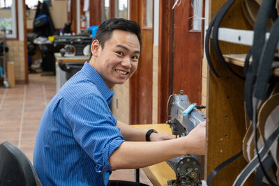 Jason, a technician at the Lethbridge Orthotics in Alberta, smiling as he works on an orthotic device.