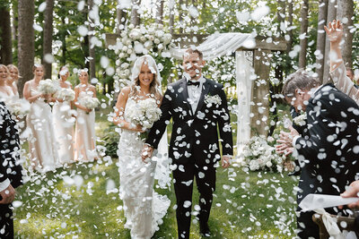 An outdoor wedding ceremony where guests are throwing confetti at the Bride and Groom