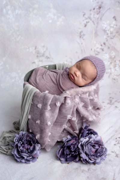 Newborn baby wrapped in purple tones for newborn photo session