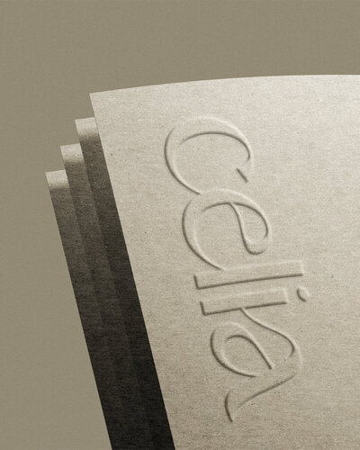 Embossed logo design for Celia on textured neutral paper, showcasing timeless branding and premium brand materials.