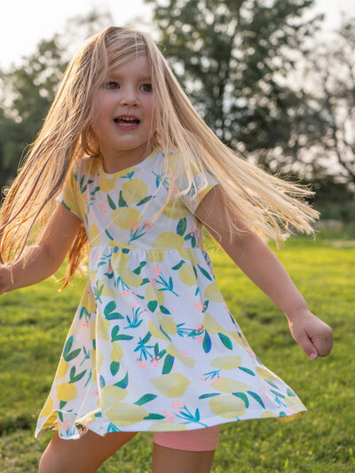 A young child twirls as her dress and hair flow around her.