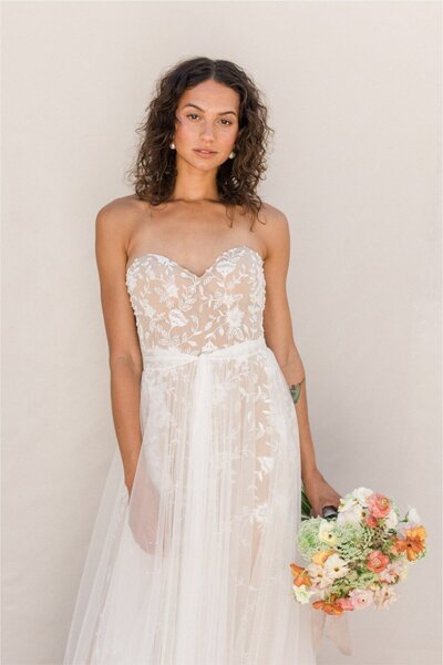 Get ready to turn heads in this delicate gown of soft netting and ethereal lace details. Topped off with a plunging v-neck bodice of Jezzie lace.