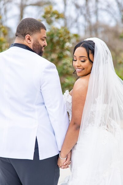 Brides veil sweeping in front of them as the groom embraces the bride