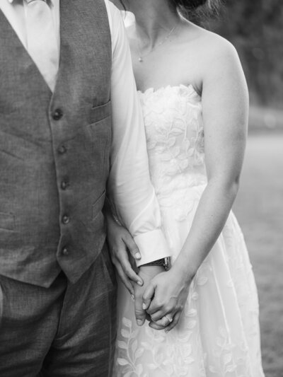 A bride and groom hold hands while facing each other and touching foreheads together. They look very happy and lovingly at each other on their wedding day.