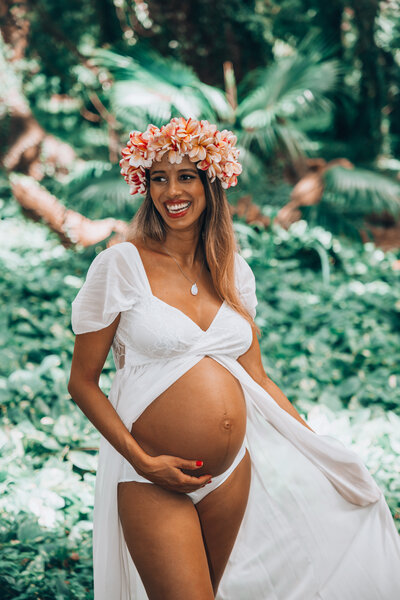 A maternity photoshoot with a new mom in the forrest in Maui. She is wearing all white and glowing from with her baby girl arriving soon