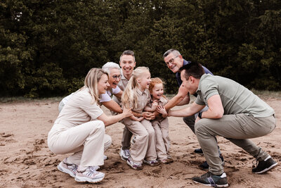Familie met opa oma oom papa en mama geeft twee klein kinderen een knuffel
