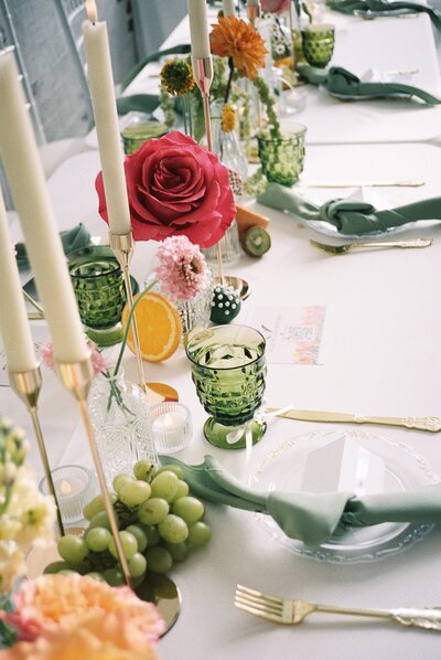 colorful wedding reception table with green glassware and taper candles
