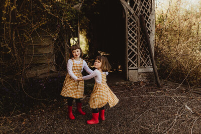 sisters in wellies playing outside