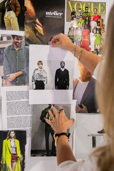 person pinning fashion photographs and articles on a mood board for style inspiration