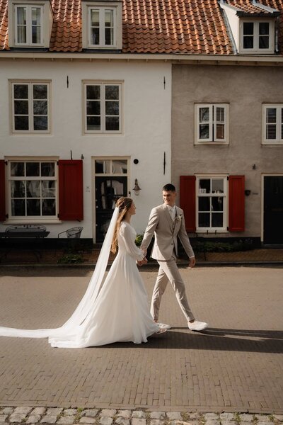 Getrouwd koppel wandelt hand in hand in de stad, gefotografeerd door trouwfotograaf Julia de Groot